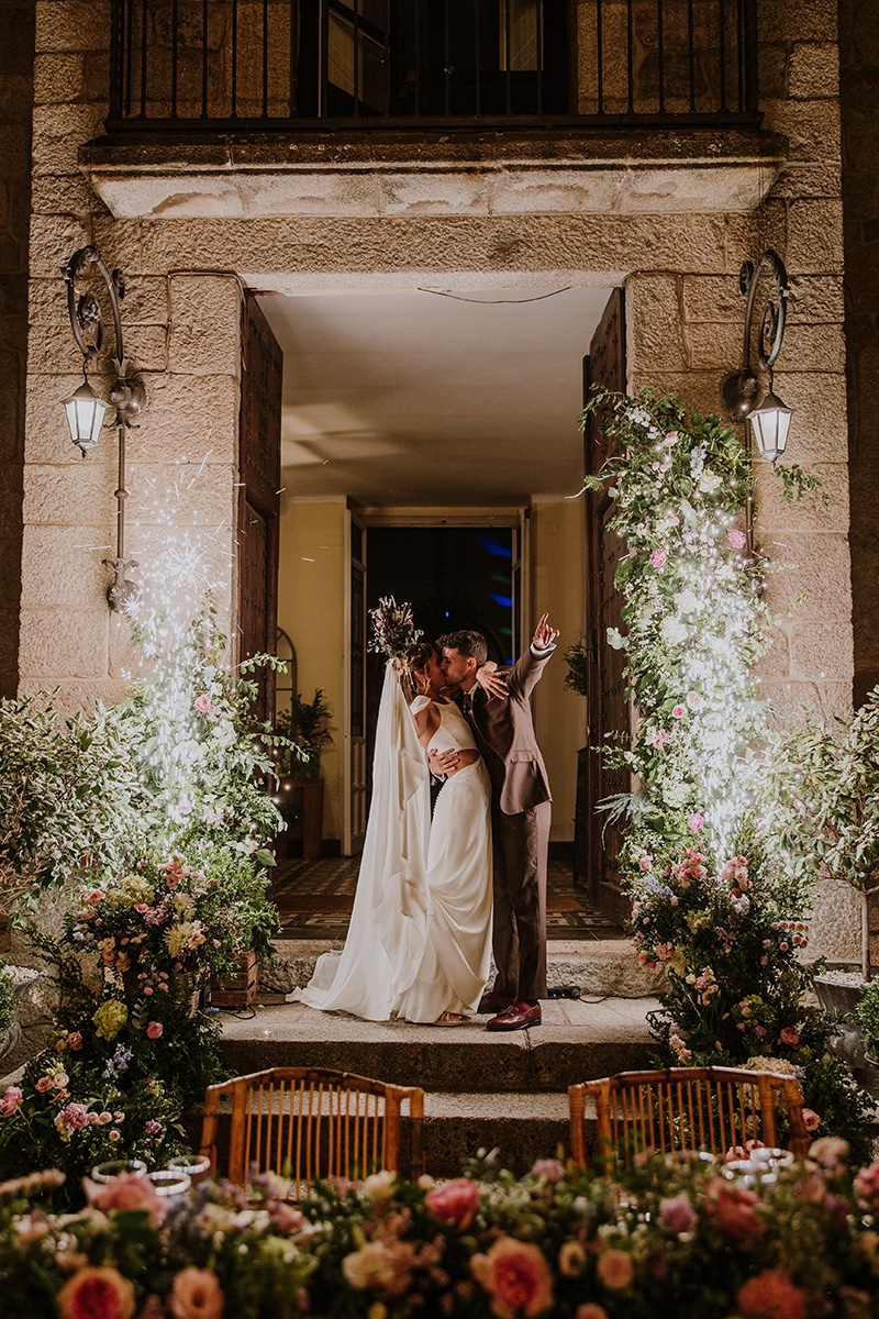 Tamara y Alex besándose durante el banquete de su boda, organizada por la wedding planner La Alquimista Eventos en la Finca El Gasco, con decoración rústico-chic y flores.