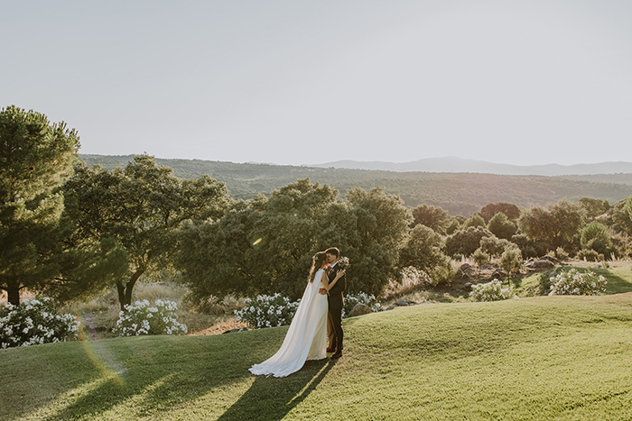 Tamara y Álex abrazados en su boda en la finca El Gasco, con paisaje natural de fondo.